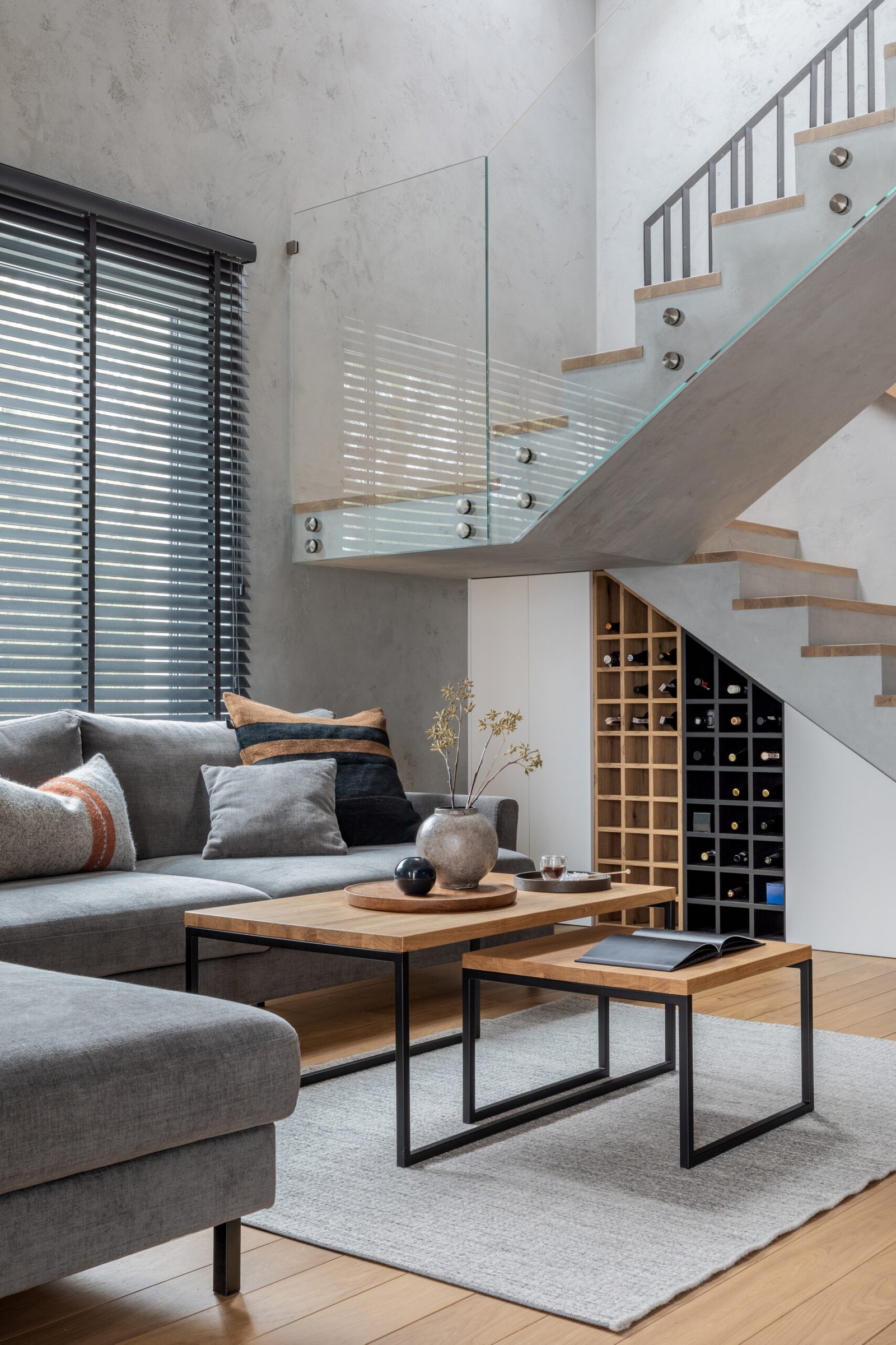 Stylish living room interior with corner grey sofa and winding staircase.